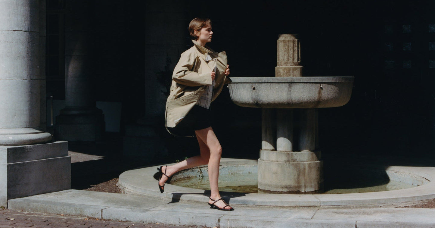 Woman walking past a fountain in an urban setting